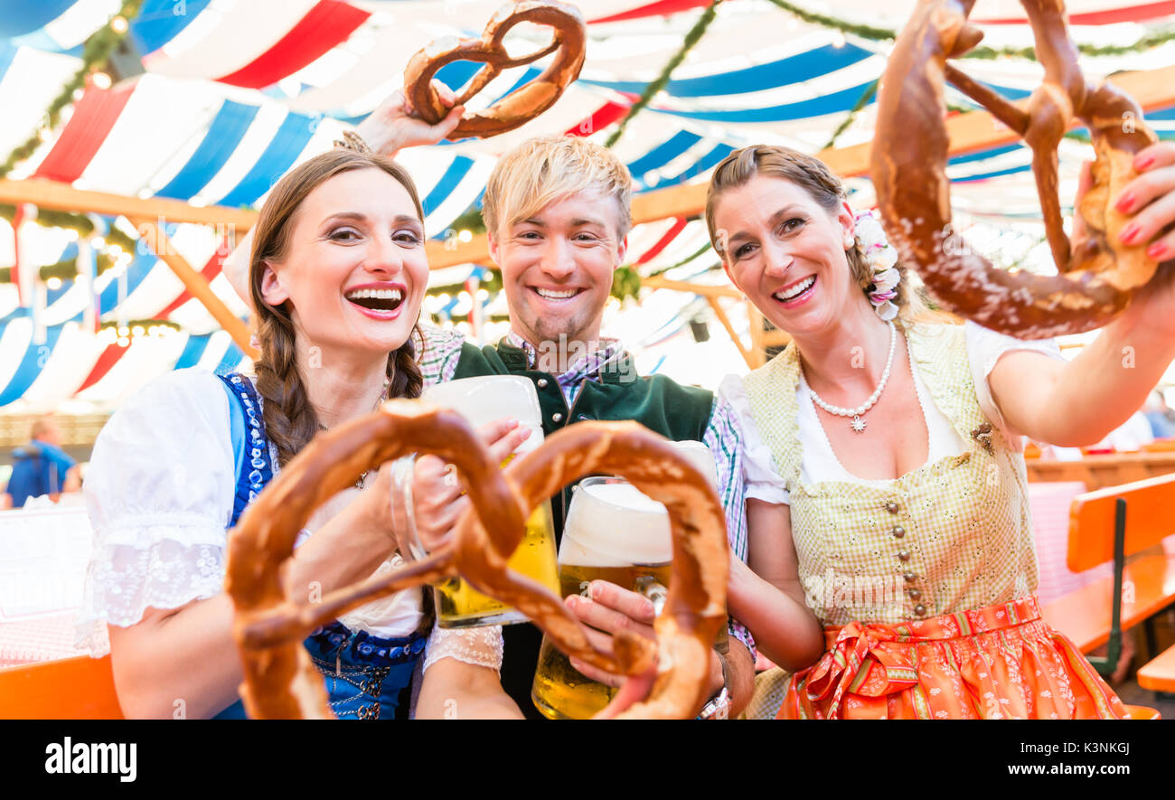 Freunde mit riesigen Brezeln im bayerischen Bierzelt Stockfoto