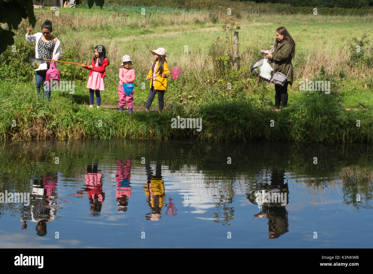 Familie mit drei Kindern in bunten Kleidern mit Netzen im Fluss in der Nähe von Godalming, Surrey, Großbritannien Stockfoto