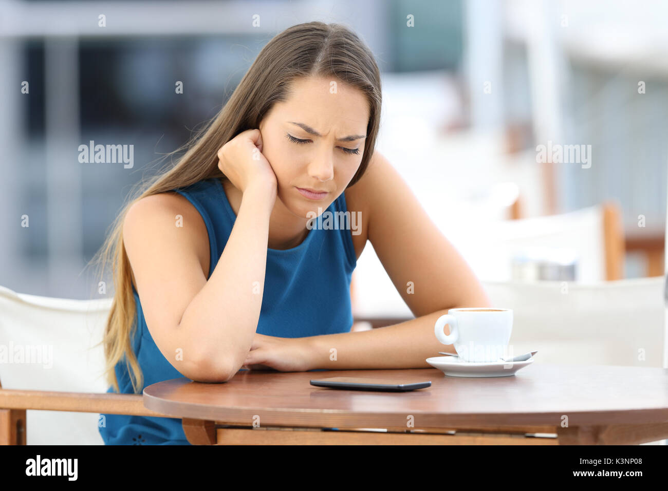 Einzelne traurige Frau warten auf ein Mobiltelefon Nachricht oder rufen Sie in einem Café sitzen Stockfoto