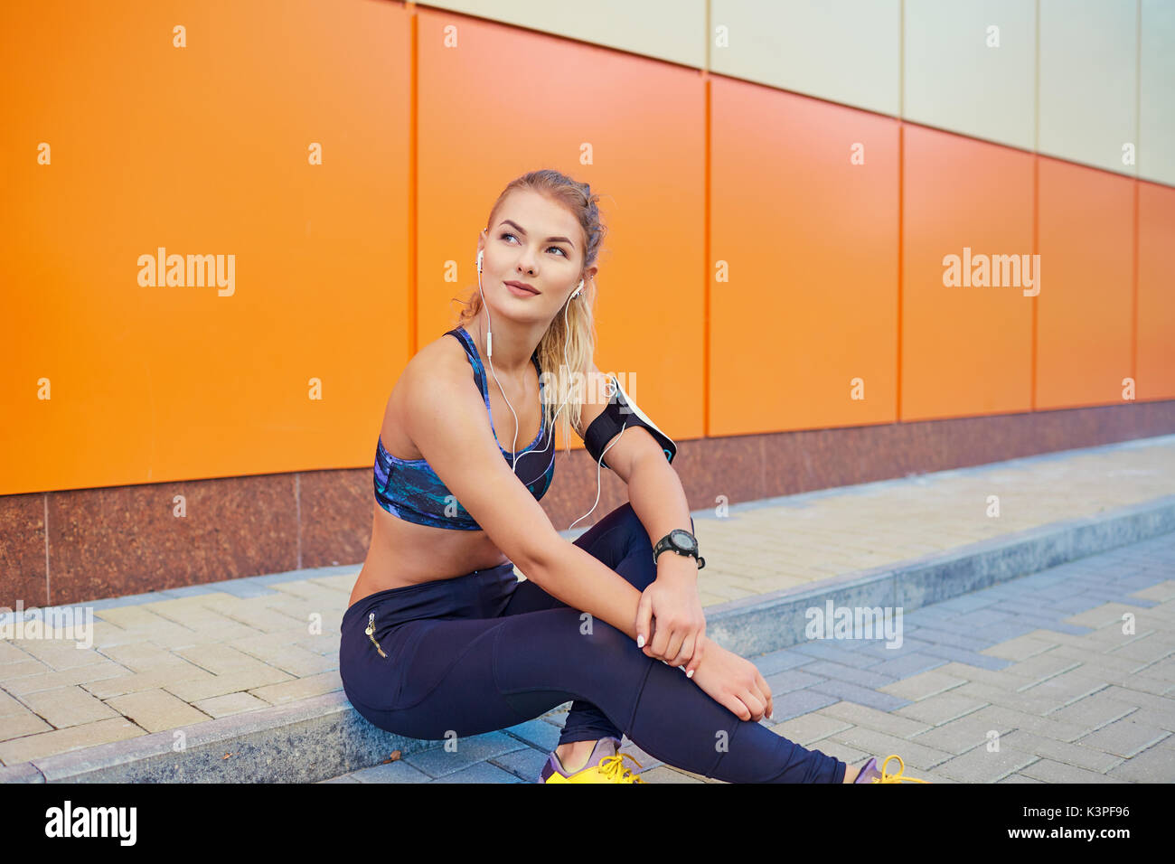 Mädchen sport Musik hören mit Kopfhörern sitzen auf Orange Stockfoto