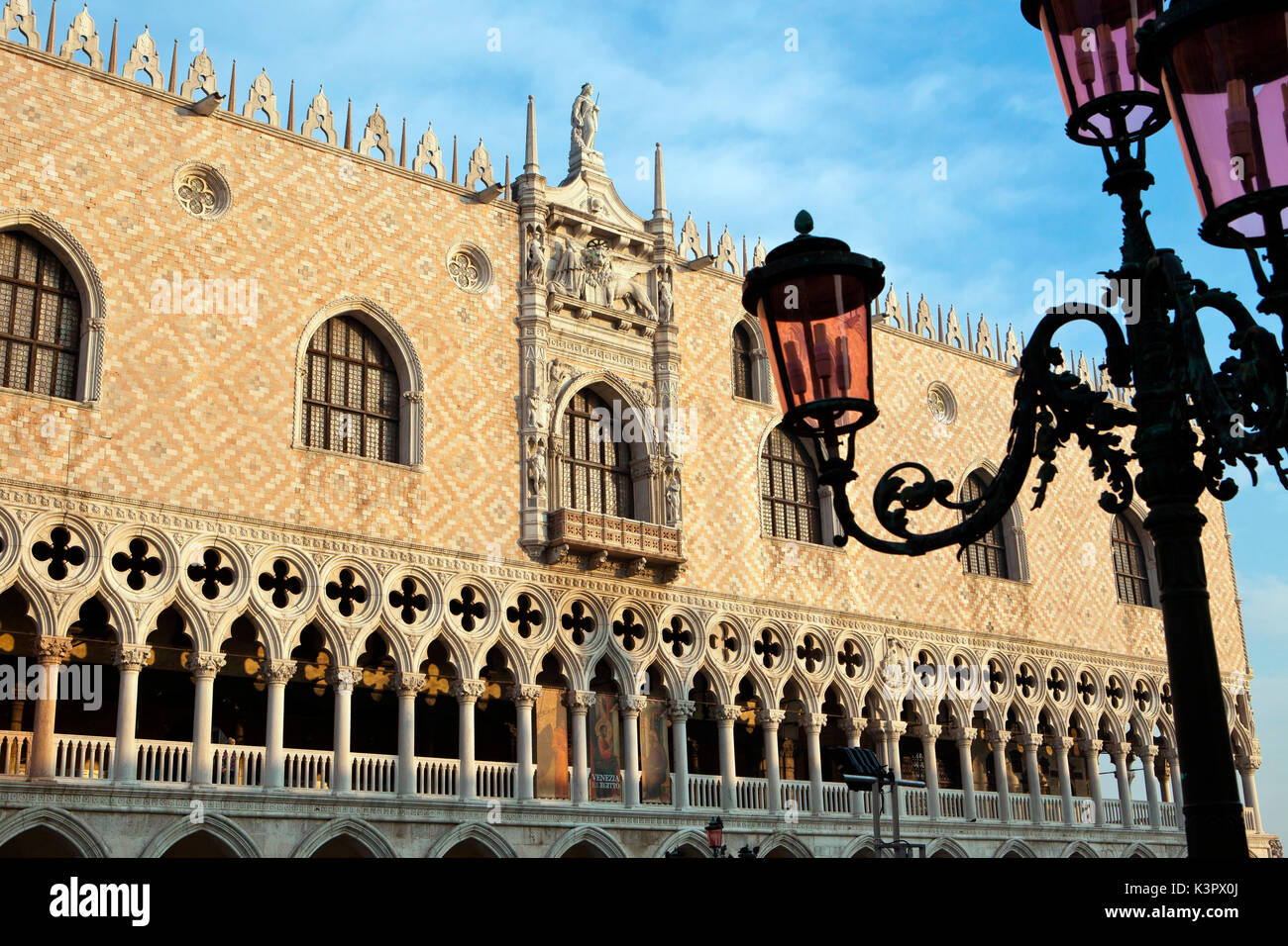 Die Fassade des Dogenpalastes einschließlich einer unteren Abschnitt besteht aus einem Erdgeschoss Kolonnade unter eine offene Loggia. Im Vordergrund ein typisch venezianischen Lamp Post, Venedig, Venetien Italien Europa Stockfoto