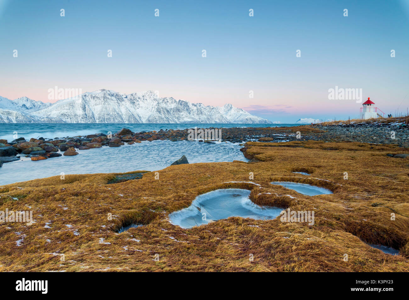 Gras bedeckt mit Eis Frames den Leuchtturm von gefrorenen Meer in der Dämmerung Djupvik Lyngen Alpen Tromsø Norwegen Europa umgeben Stockfoto