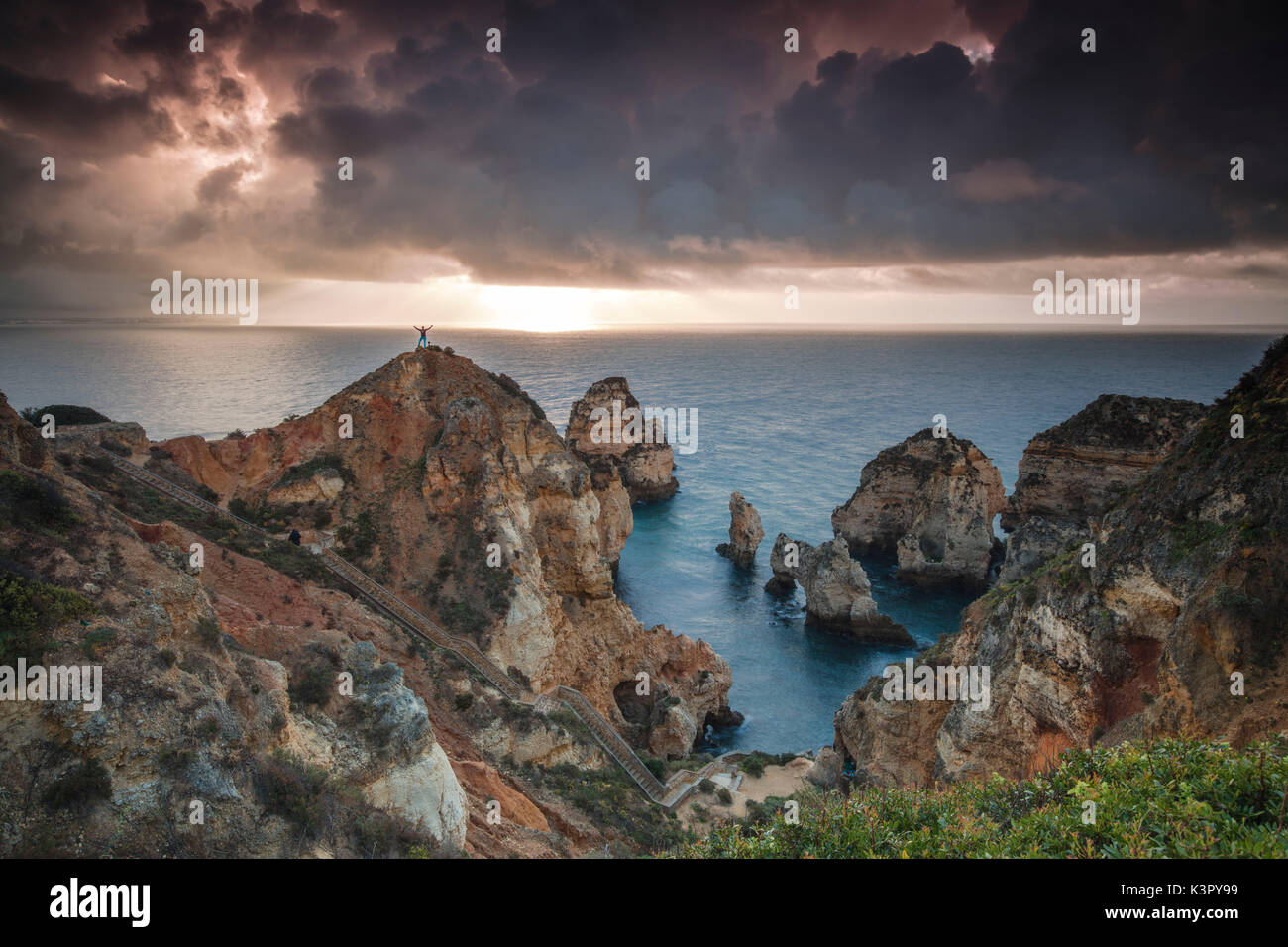 Wanderer auf Klippen am Meer unter dem bewölkten Himmel bei Sonnenaufgang Ponta da Piedade Lagos Algarve Portugal Europa umgeben Stockfoto