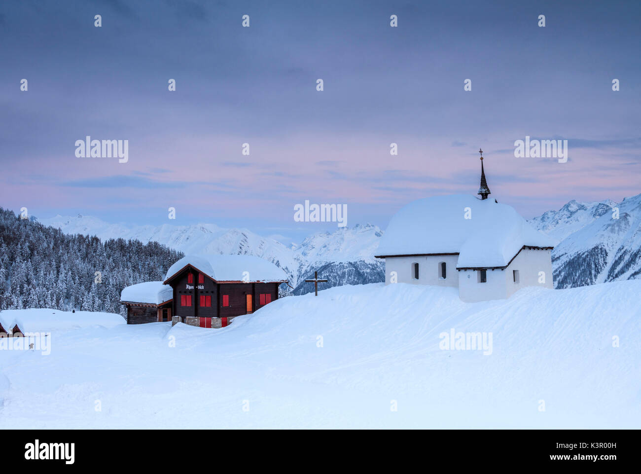 Sonnenuntergang Frames die Berghütten und Kirche mit Schnee Bettmeralp Bezirk Raron im Kanton Wallis Schweiz Europa abgedeckt Stockfoto