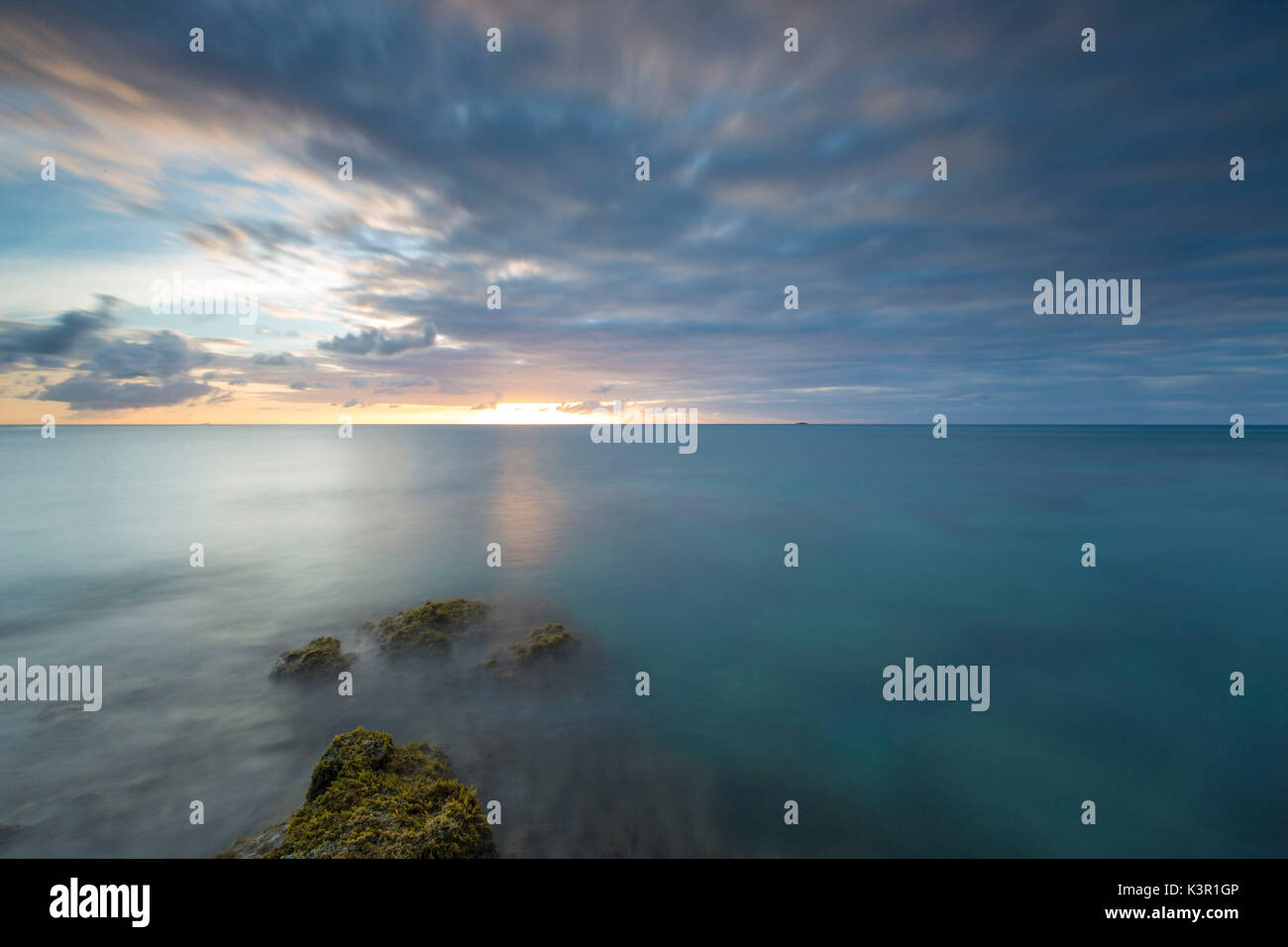 Das Licht des Sonnenuntergangs spiegeln sich in das blaue Meer Hawksbill Bay Karibik Antigua und Barbuda Leeward Islands West Indies Stockfoto