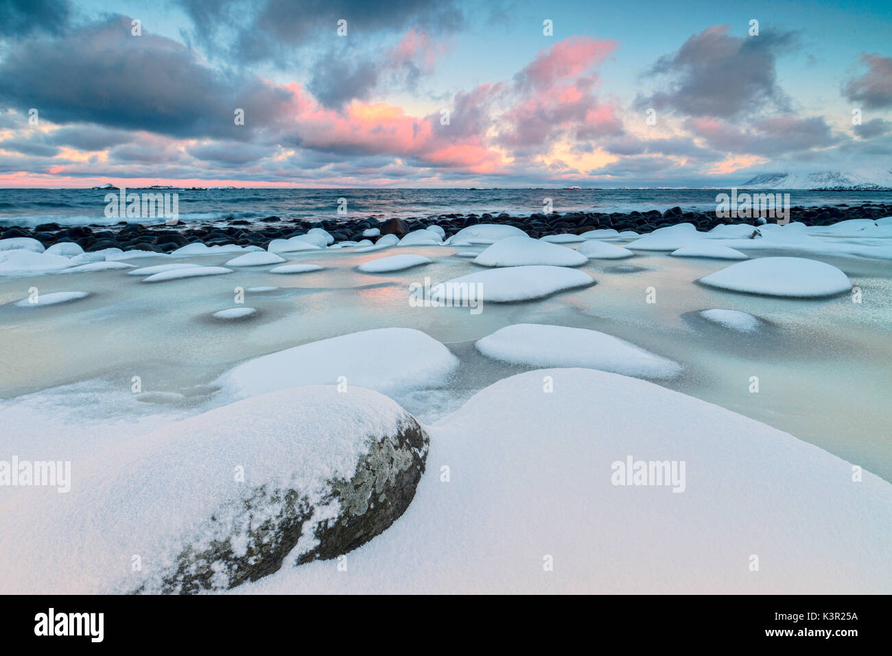 Dawn auf dem kalten Meer durch verschneite Felsen durch Wind und Eis in Eggum Insel Vestvagøy Lofoten norwegen Europa geformt umgeben Stockfoto
