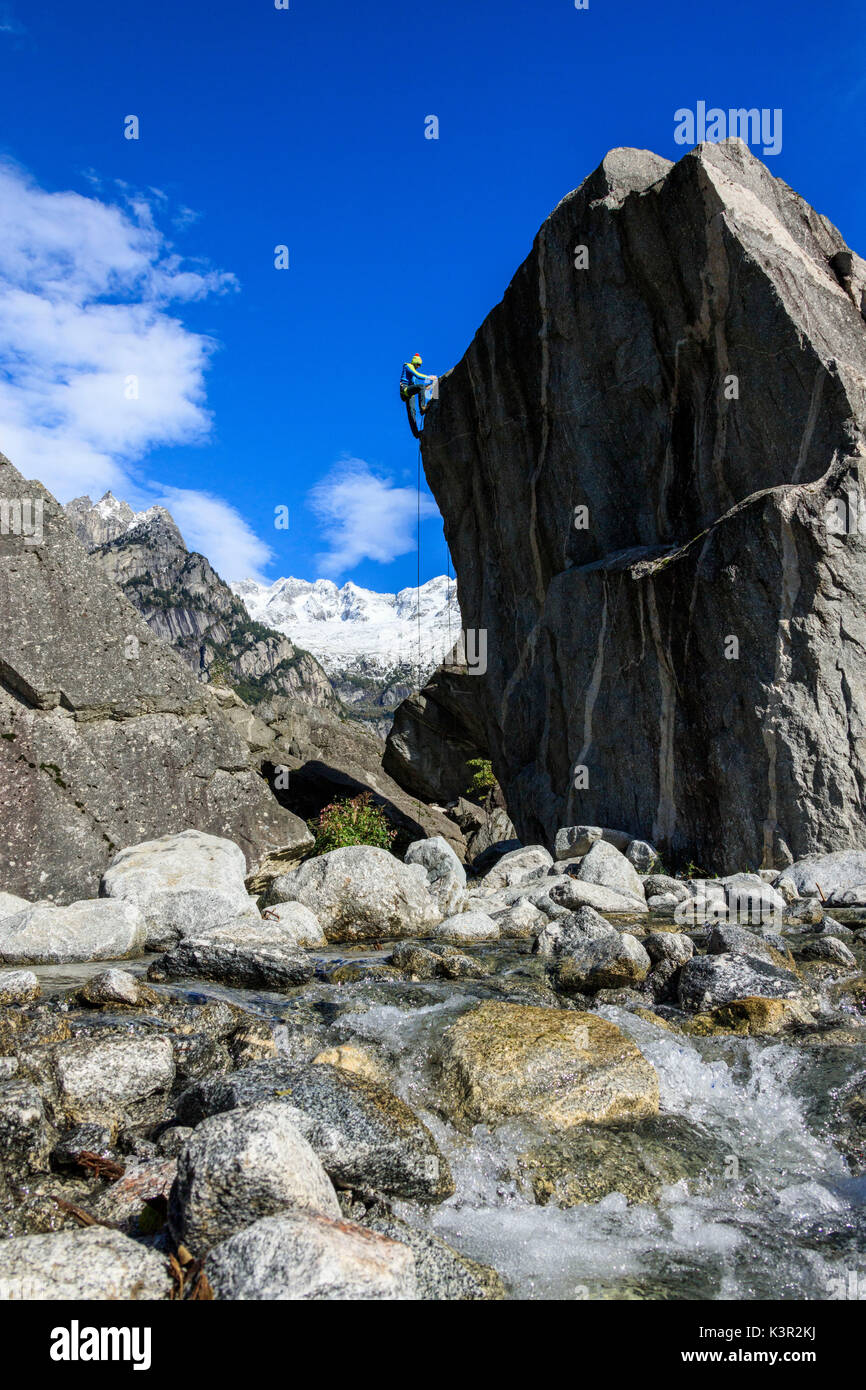 Kletterer auf steilen Felswand im Hintergrund blaue Himmel und die schneebedeckten Gipfel der Alpen Masino Tal Veltlin Lombardei Italien Europa Stockfoto