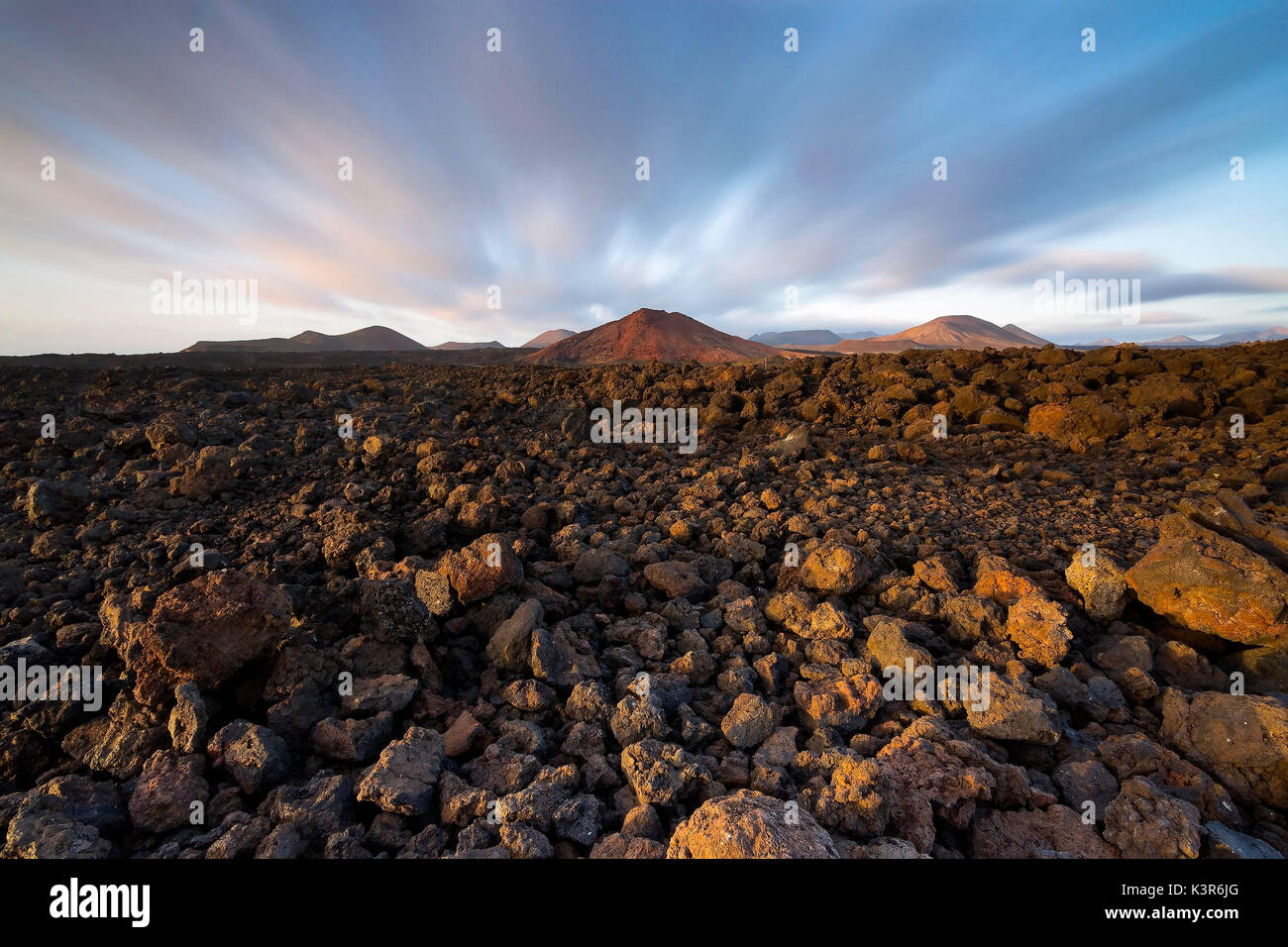 Vulkanische Gesteine mit Vulkanen und ziehenden Wolken im Hintergrund - Lanzarote, Kanarische Inseln Stockfoto
