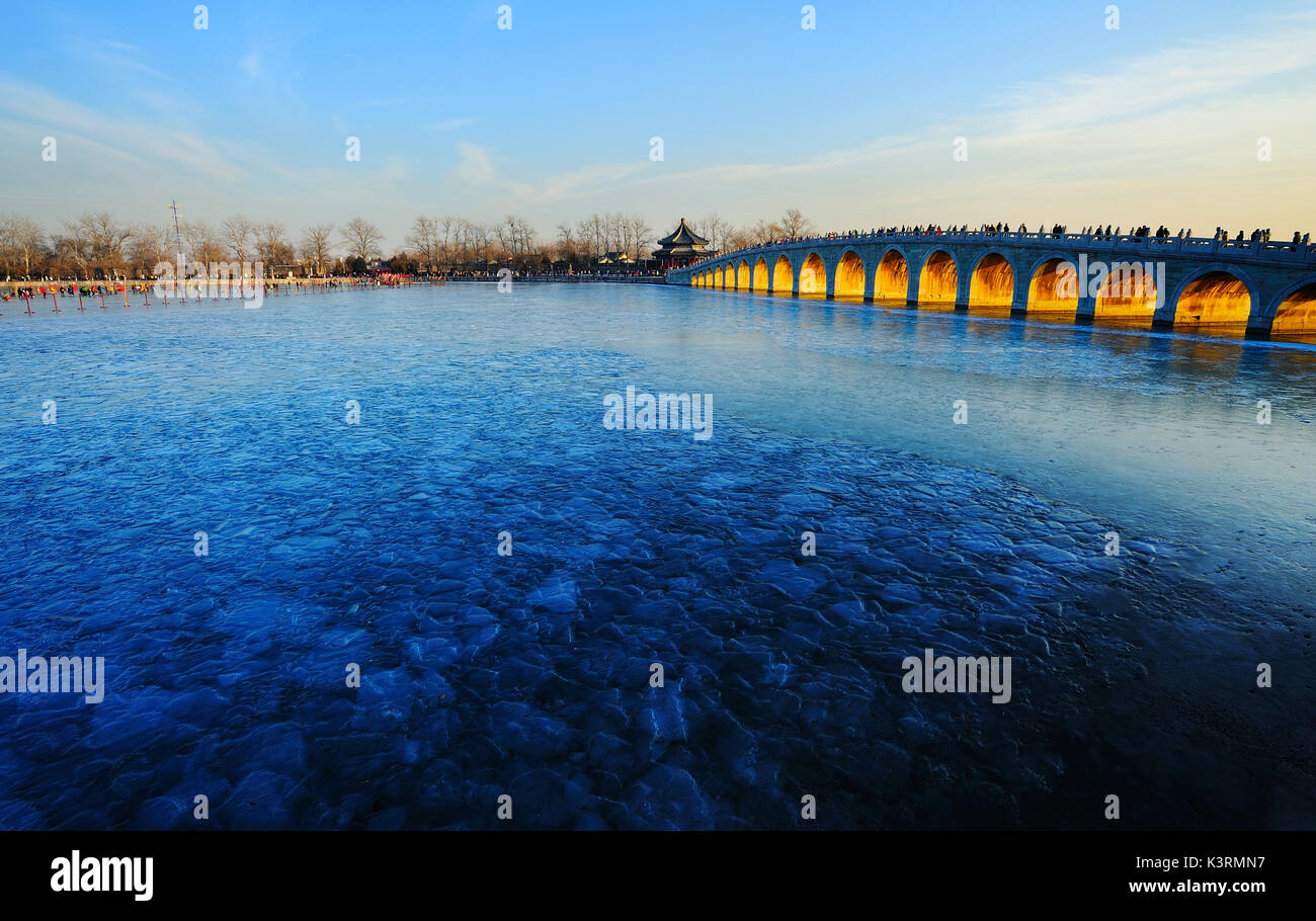 Der Sommerpalast im Winter, Kunming See wurde eingefroren, die Abendsonne durch die Brücke öffnen Der 17 Bogenbrücke. Stockfoto