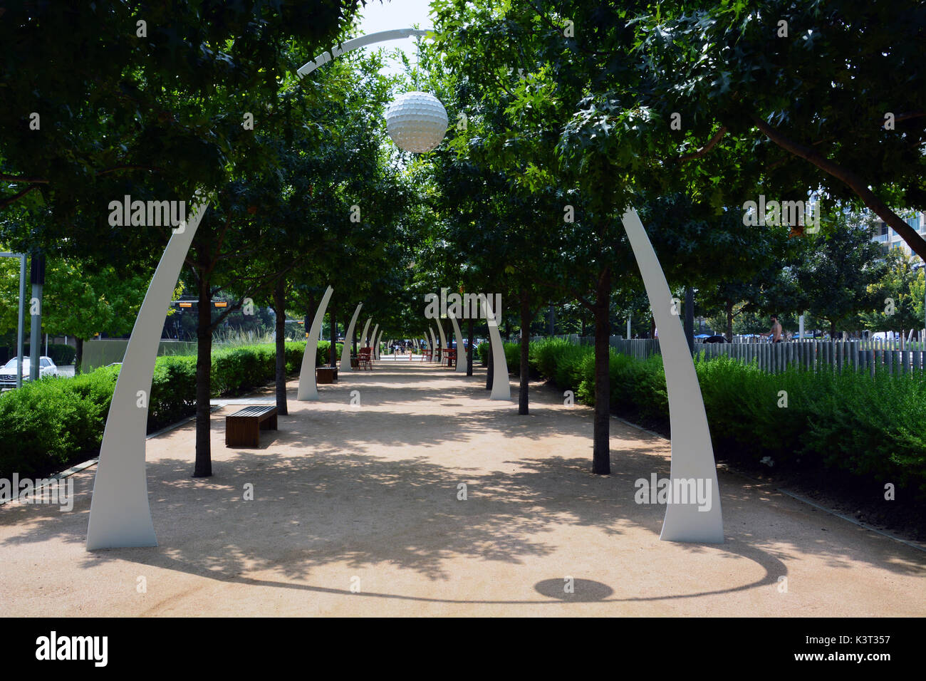 Die Eiche von Bäumen gesäumten Pfad am Klyde Warren Park in Dallas bietet Sitzgelegenheiten und dekorative Torbögen. Stockfoto