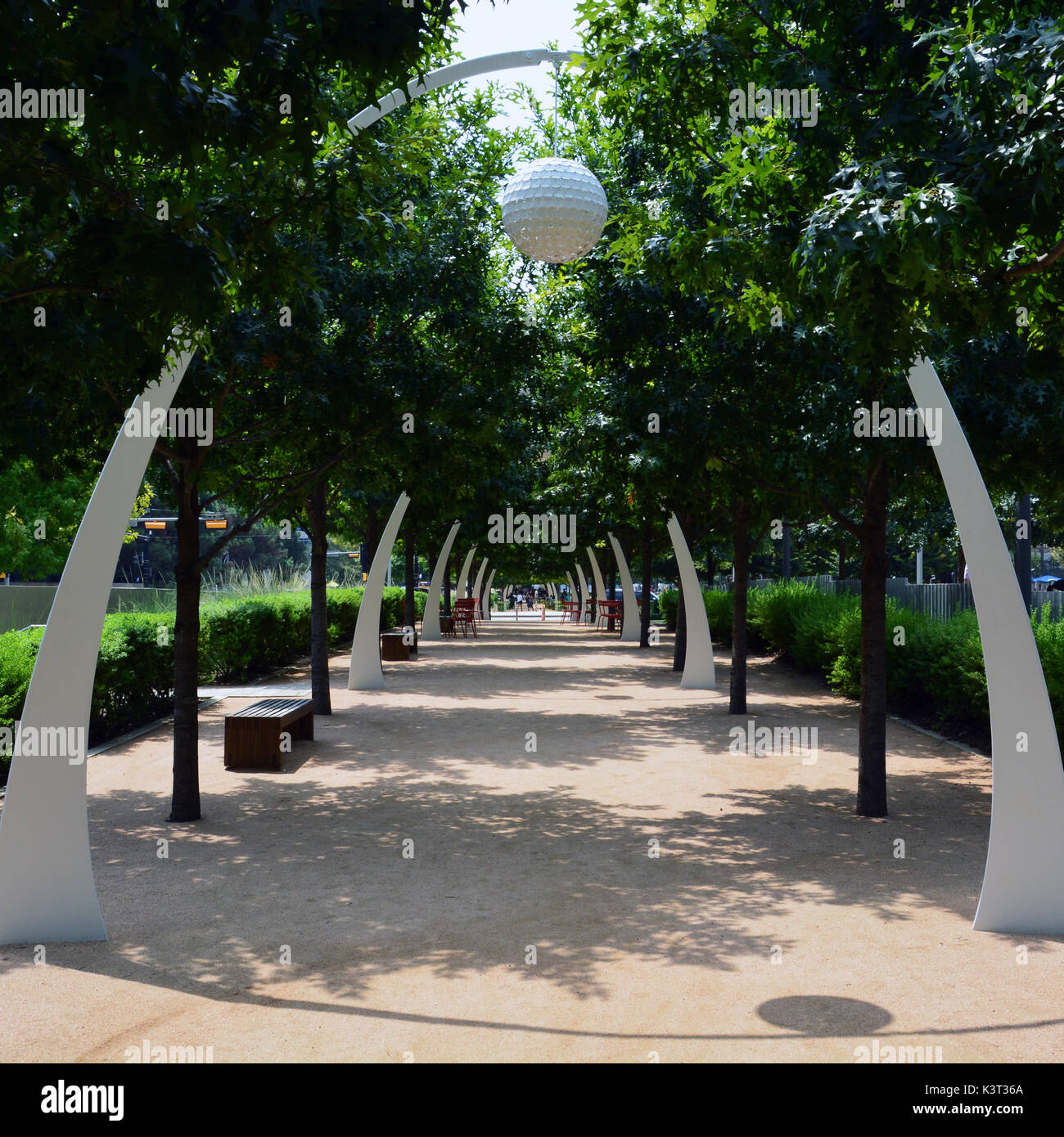 Die Eiche von Bäumen gesäumten Pfad am Klyde Warren Park in Dallas bietet Sitzgelegenheiten und dekorative Torbögen. Stockfoto