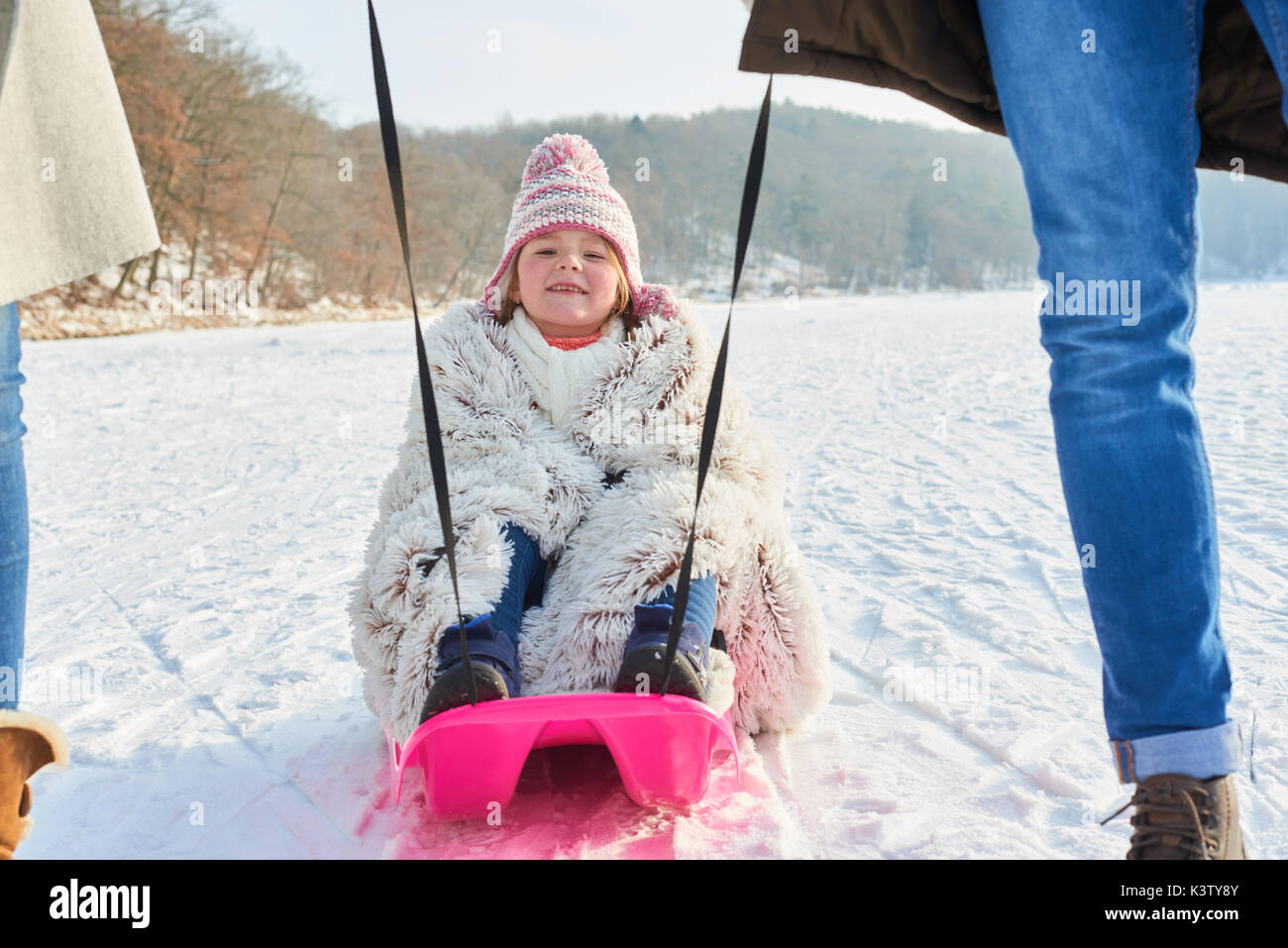 Kind Rodeln oder Rodeln auf Schnee mit Ihren glücklichen Familie Stockfoto