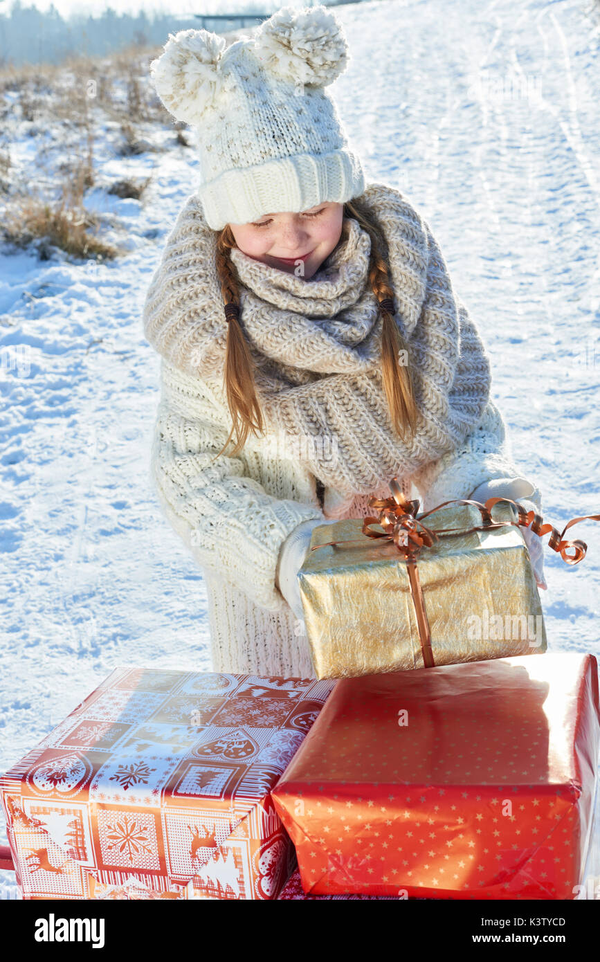 Mädchen bringt Weihnachten überraschung präsentiert mit Schlitten im Winter Stockfoto