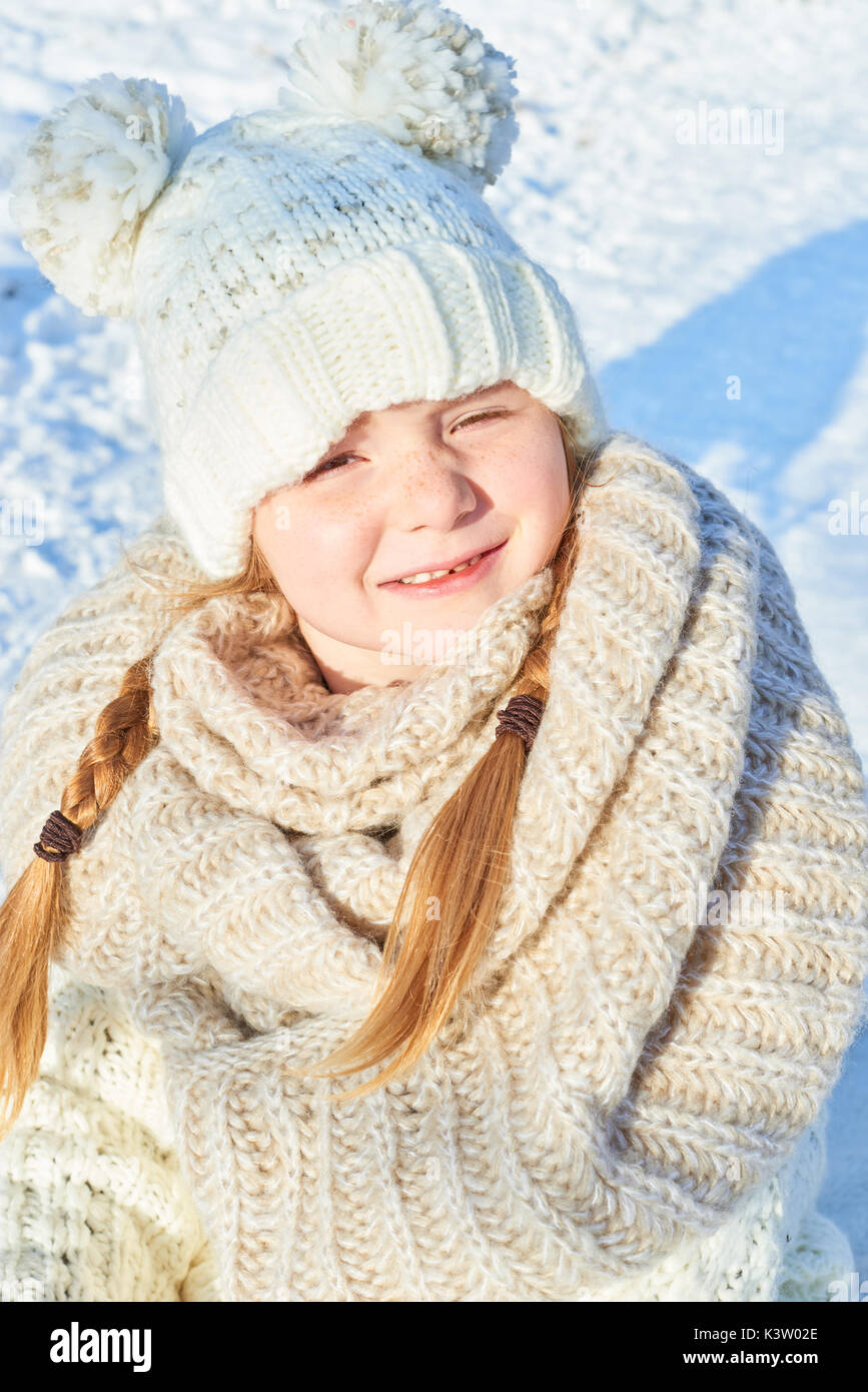 Glückliches Kind mit der Lagerung Kappe und Zöpfe im Winter Stockfoto