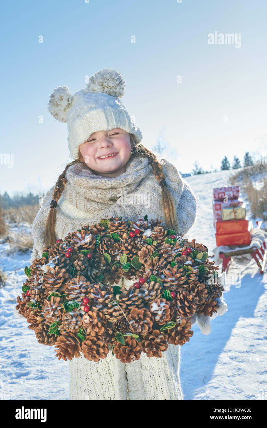 Glückliches Kind mit Weihnachten Adventskranz im Schnee Stockfoto
