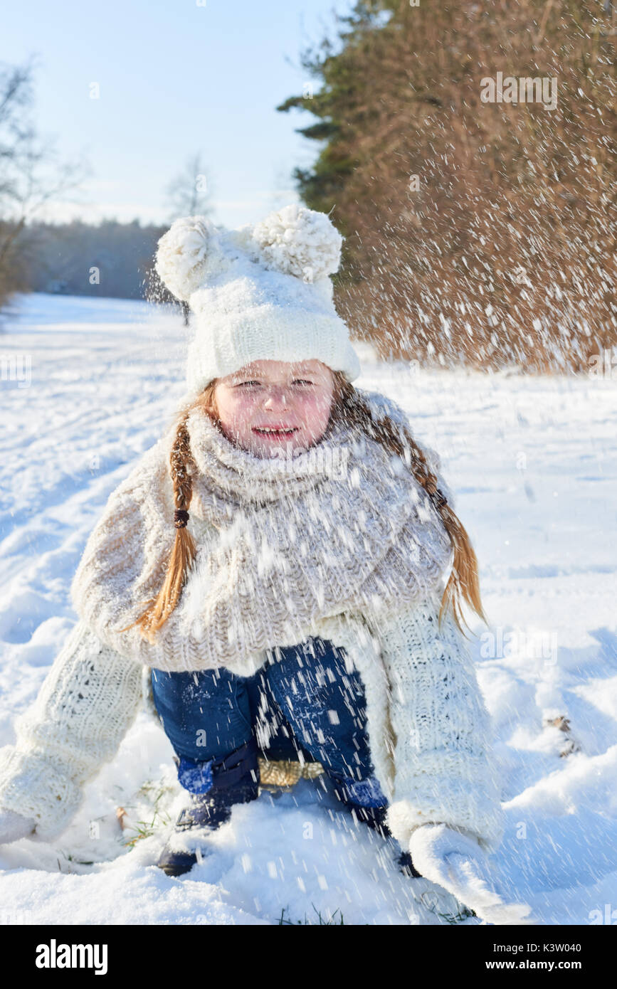 Glückliches Kind spielen und werfen Schnee im Winter und Spaß haben Stockfoto