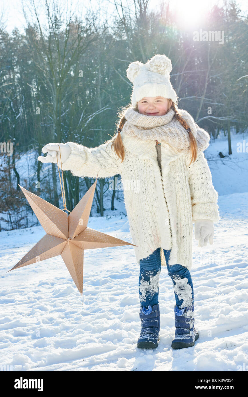 Kind hält Christmas Star im Winter in der Natur im Schnee Stockfoto