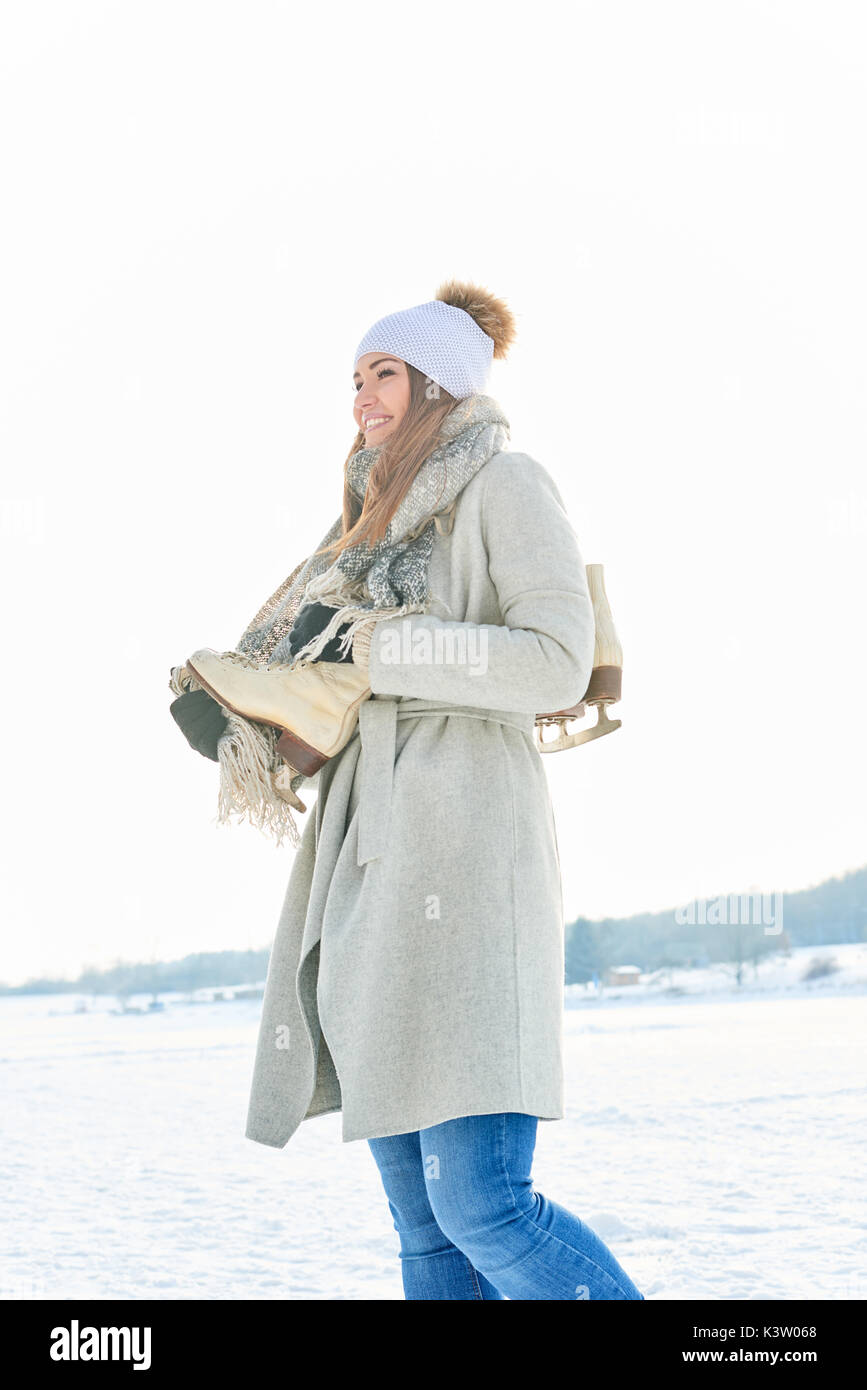 Junge Frau freut sich über Winter und trägt Ihr schlittschuhen auf ihrer Schulter Stockfoto