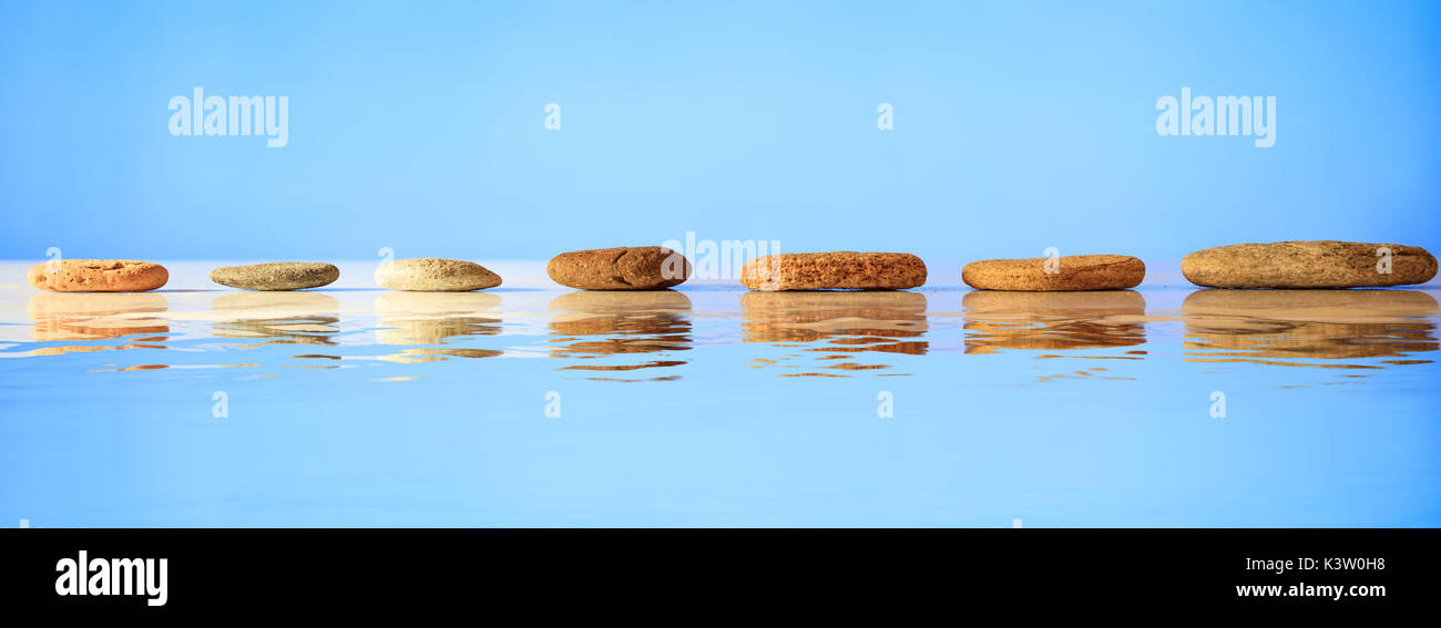 Zen Trittsteine auf blauem Hintergrund, Reflexionen auf dem Wasser Stockfoto