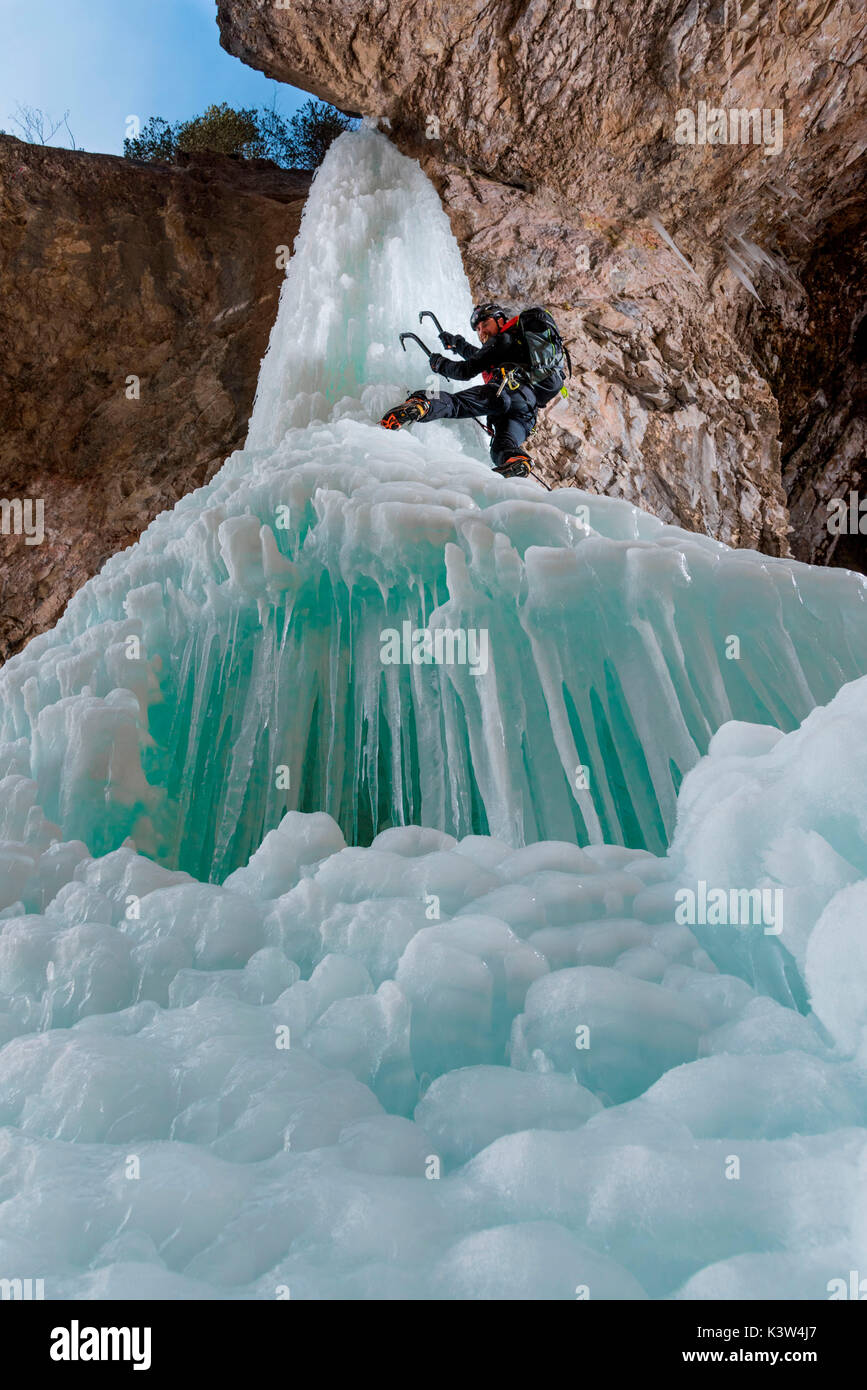 Dolomiten, Fassatal, Italien, Europa, Trentino, Alpen. Eis-Kaskaden, klettert ein Mann mit einem Eispickel, Eisblock eingefroren in den europäischen Alpen. Stockfoto