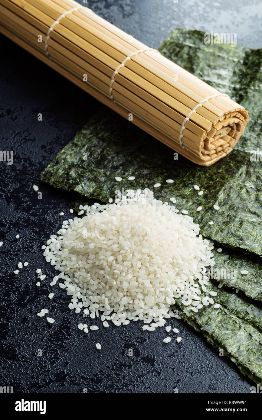 Grüne nori Blatt, Reis und Bambus Matte auf Schwarzen Tisch. Stockfoto