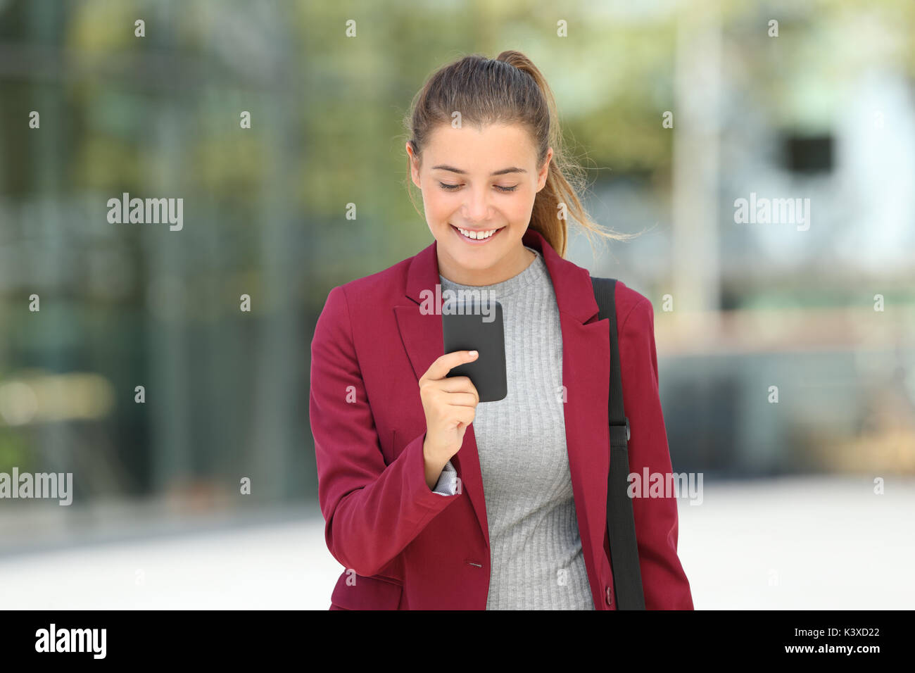 Vorderansicht Portrait eines einzelnen Executive lesen telefonische Nachrichten und Wandern in Richtung Kamera auf der Straße Stockfoto