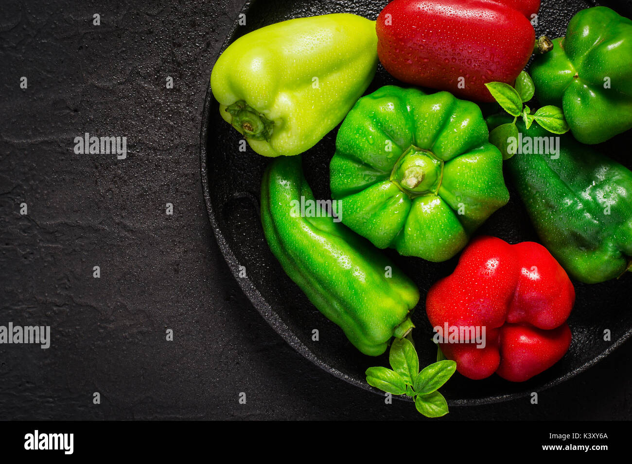 Verschiedene rote und grüne bel Paprika mit Wassertropfen auf gusseiserne Schale. Stockfoto