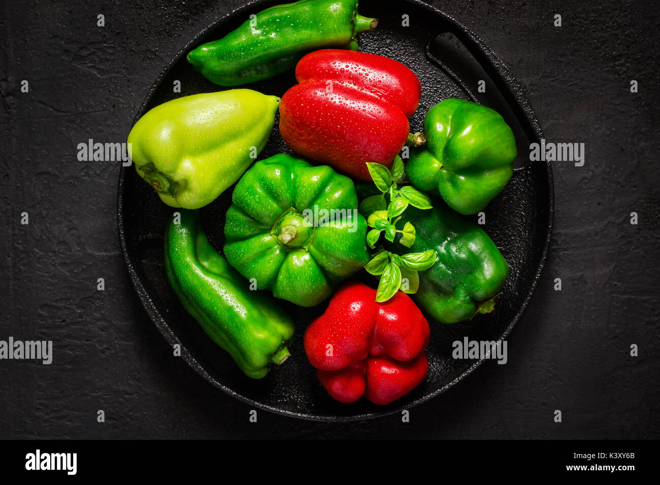 Verschiedene rote und grüne bel Paprika mit Wassertropfen auf schwarzen Hintergrund. Stockfoto
