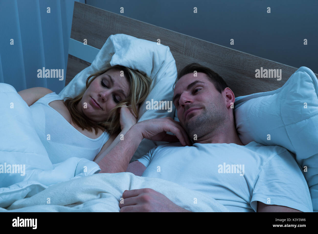 Portrait von gebohrt Paar im Bett liegend mit Decke Stockfoto