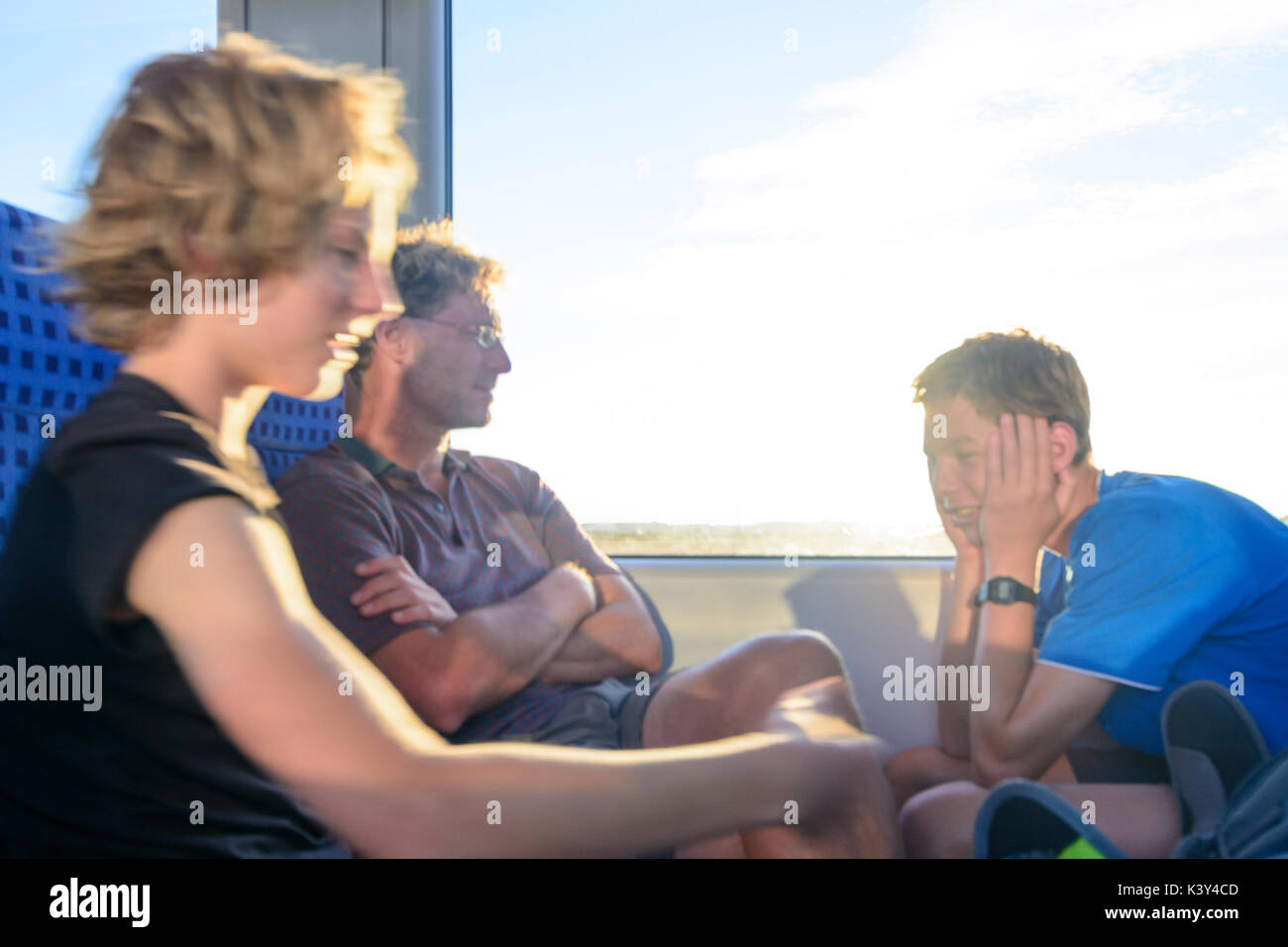 Vater Mann, 2 Jungs sitzen im Zug, Sonne, entspannt, Augsburg, Schwaben, Schwaben, Bayern, Bayern, Deutschland Stockfoto