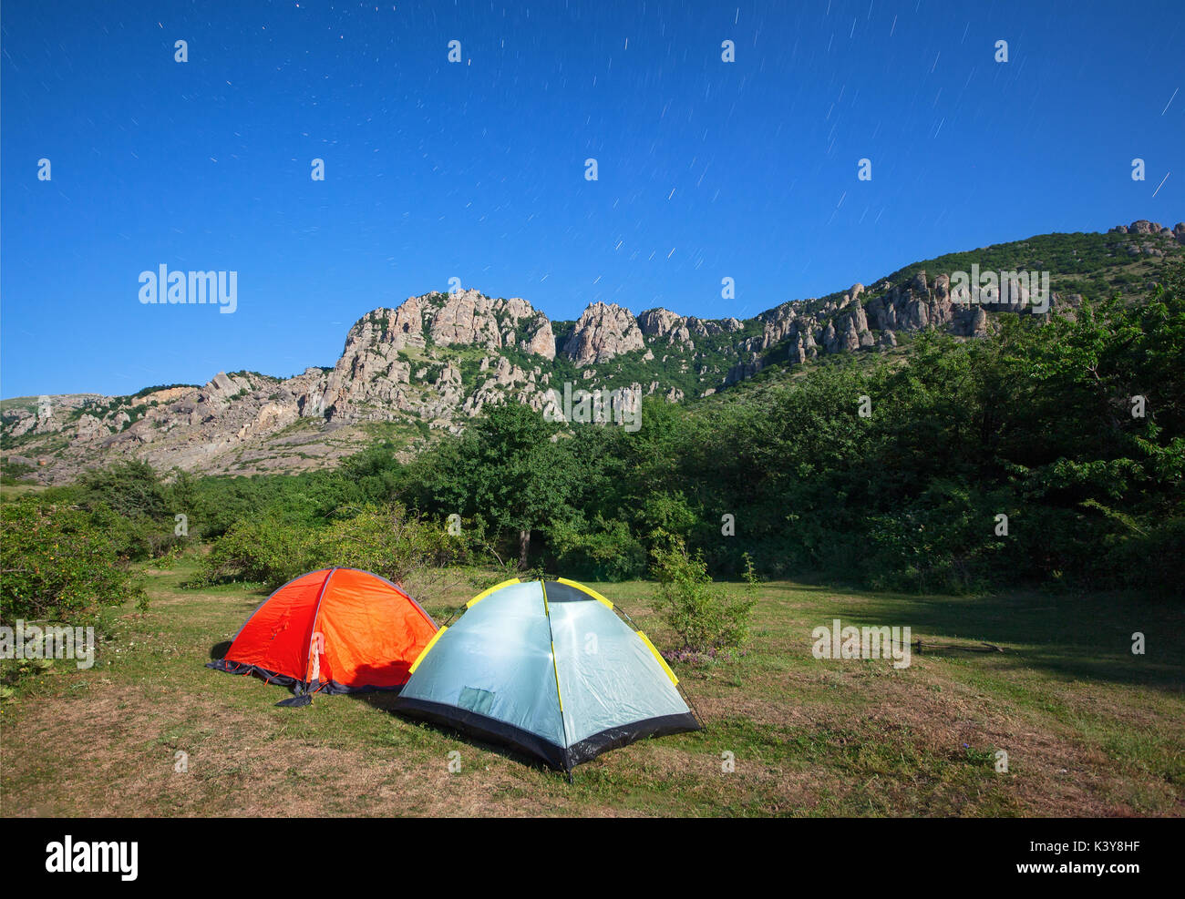Touristische Zelte in einer Lichtung in den Bergen gegen den Sternenhimmel und den Berg Stockfoto