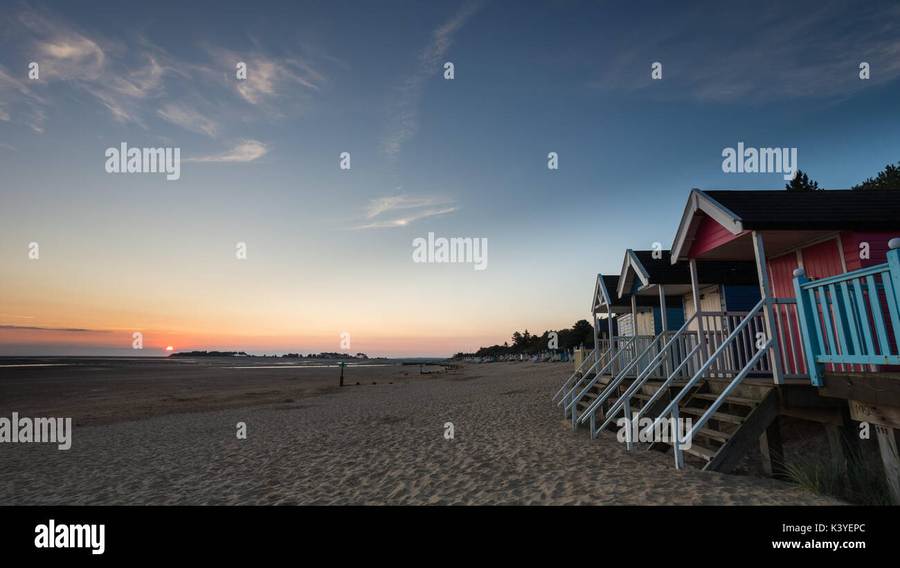 Sonnenaufgang am Brunnen Strand mit Strand Hütten im Vordergrund. Stockfoto