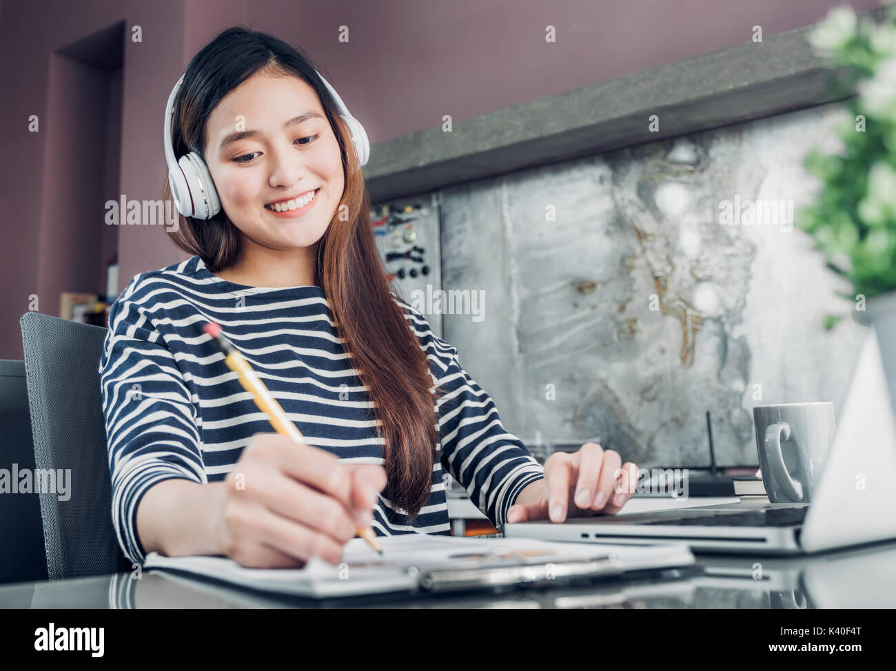 Jungen asiatischen Casual geschäftsfrau Musik hören und schreiben Bericht über Büro Schreibtisch, Arbeiten zu Hause mit Online-e-commerce job Konzept. Stockfoto