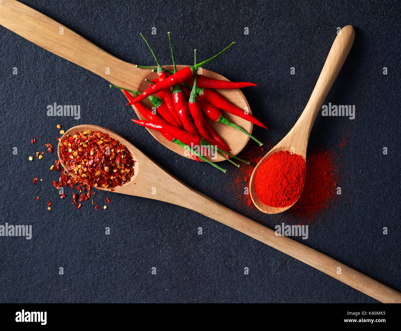 Löffel aus Holz mit Chili, Paprika Flocken und Chili Pulver gefüllt Stockfoto