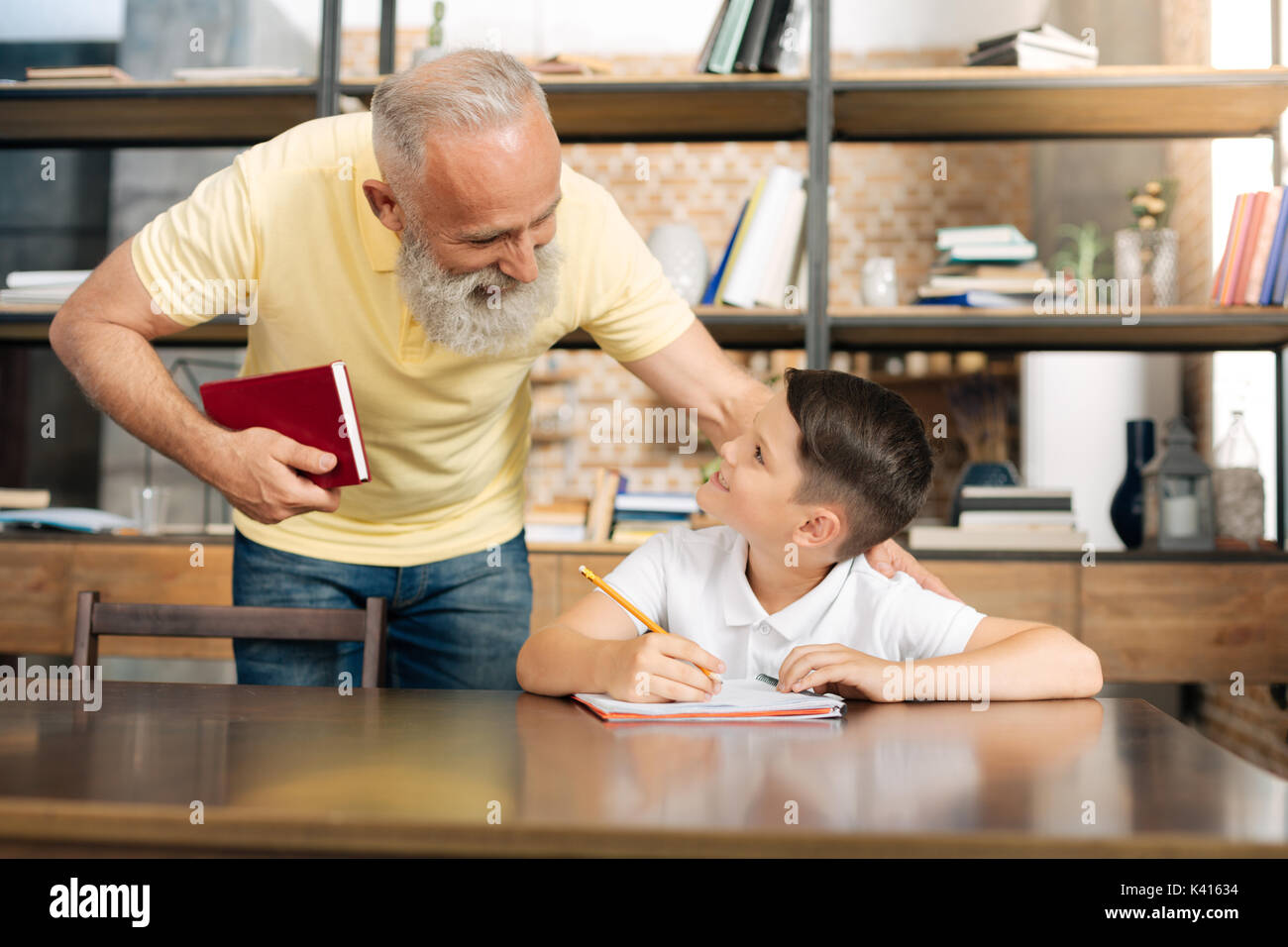 Pflege Großvater seinem Enkel Fortschritte bei der Hausaufgaben Kontrolle Stockfoto