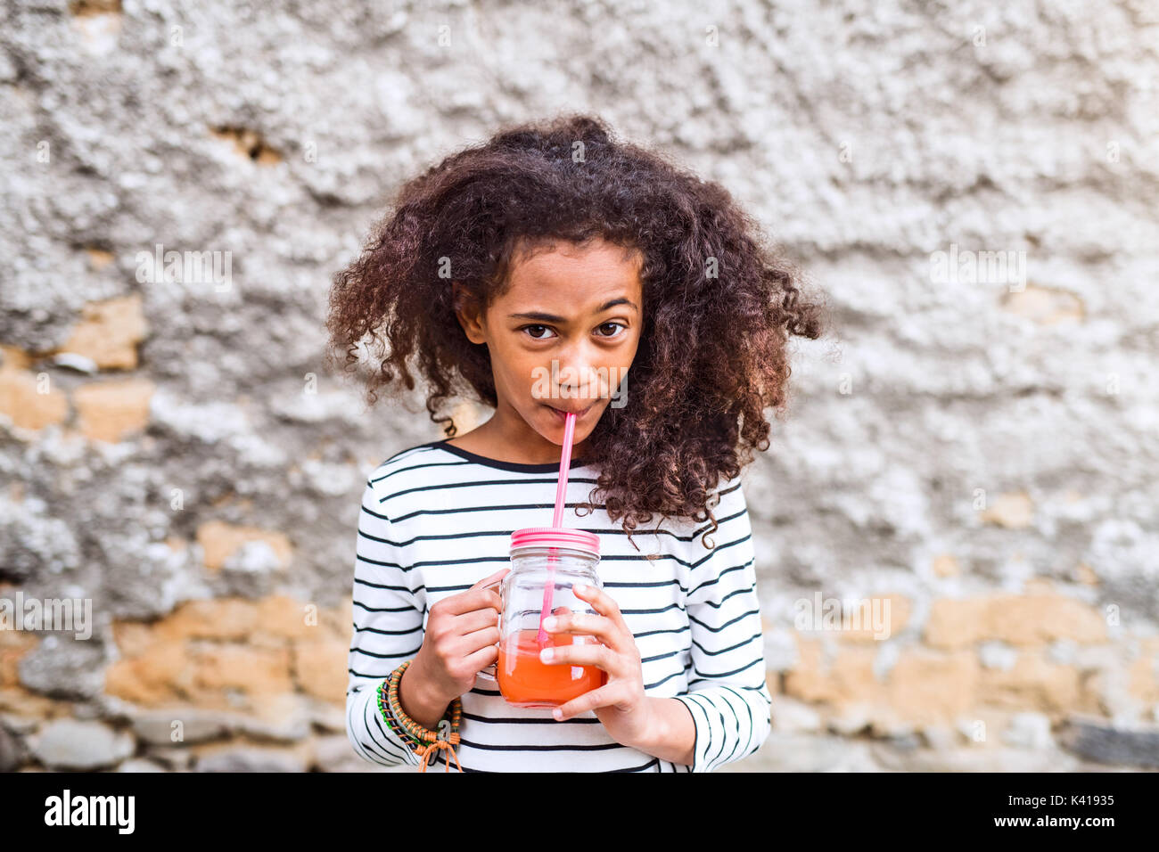 Schöne afrikanische amerikanische Mädchen Saft trinken, alte Beton Wal Stockfoto