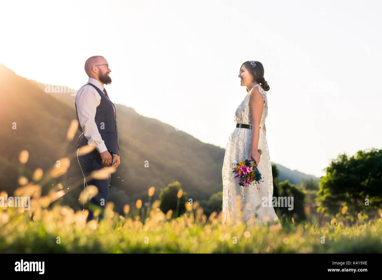 Braut und Bräutigam suchen sich gegenseitig in das Feld bei Sonnenuntergang Stockfoto