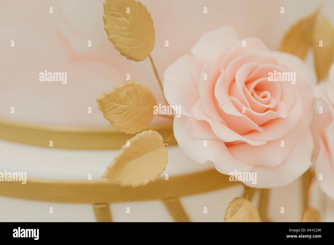 Pastellrosa und Gold Glasur Blume Hochzeitstorte Topper Stockfoto