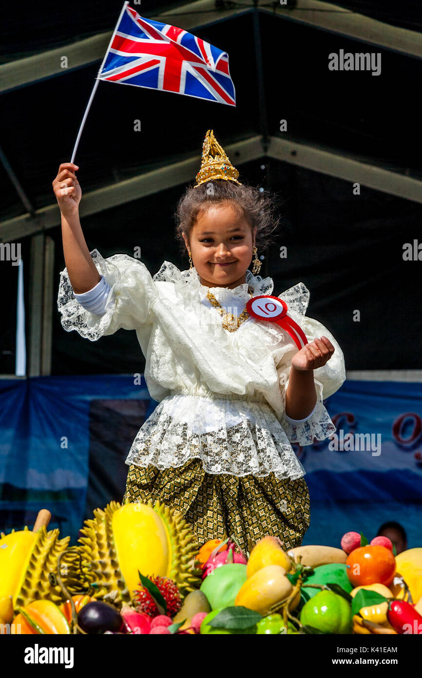 Eine angloamerikanische Thai Kind auf der Bühne im traditionellen thailändischen Kostüm winkt eine Britische Flagge, Brighton Thai Festival, Brighton, Sussex, UK Stockfoto