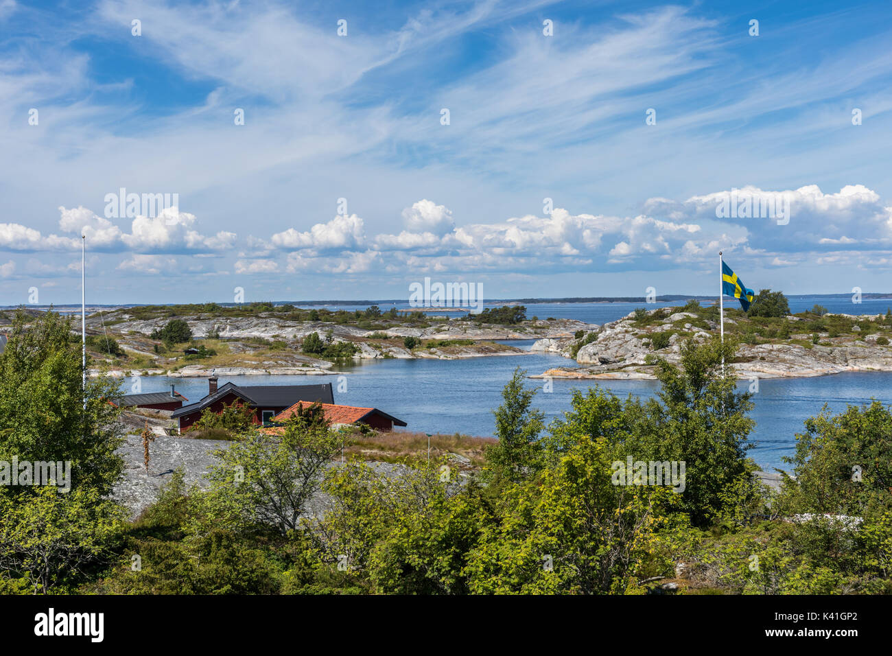Häuser am Wasser auf einer Insel in den äußeren Bereichen des Stockholmer Schären mit schwedischer Flagge Stockfoto