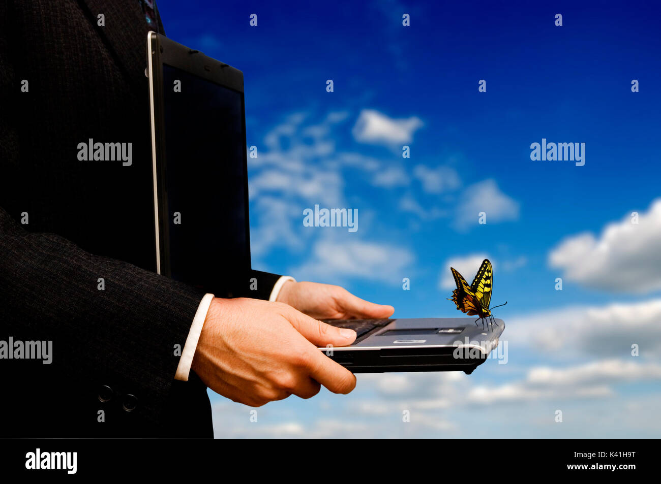 Geschäftsmann mit Laptop und ein Schmetterling sitzt auf es, Kreativität und Phantasie im Geschäft Stockfoto