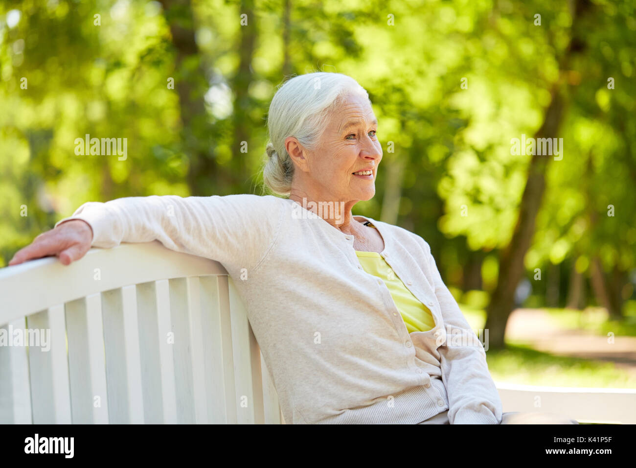 Gerne ältere Frau sitzt auf der Bank im Park Stockfoto