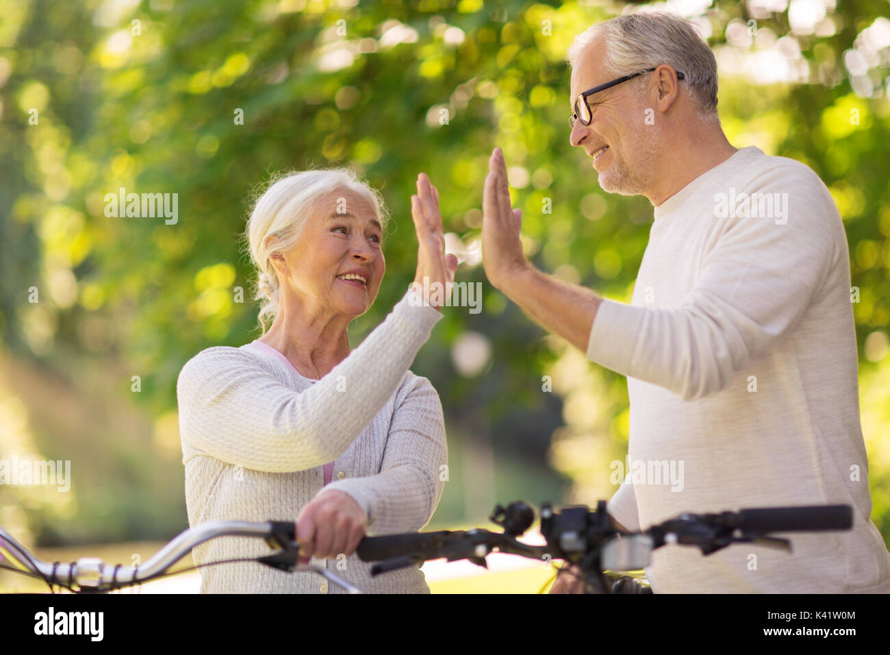 Senior Paar mit Fahrrädern hoch fünf im Park Stockfoto
