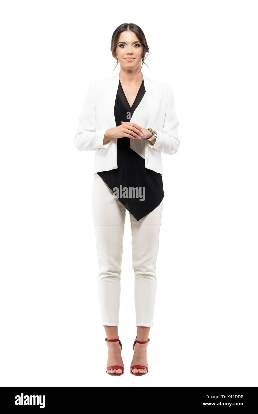 Freundlich lächelnden Business weiblichen Moderatorin im Anzug mit gefalteten Händen auf Kamera. Voller Körper Länge Porträt auf weißem Hintergrund Stockfoto