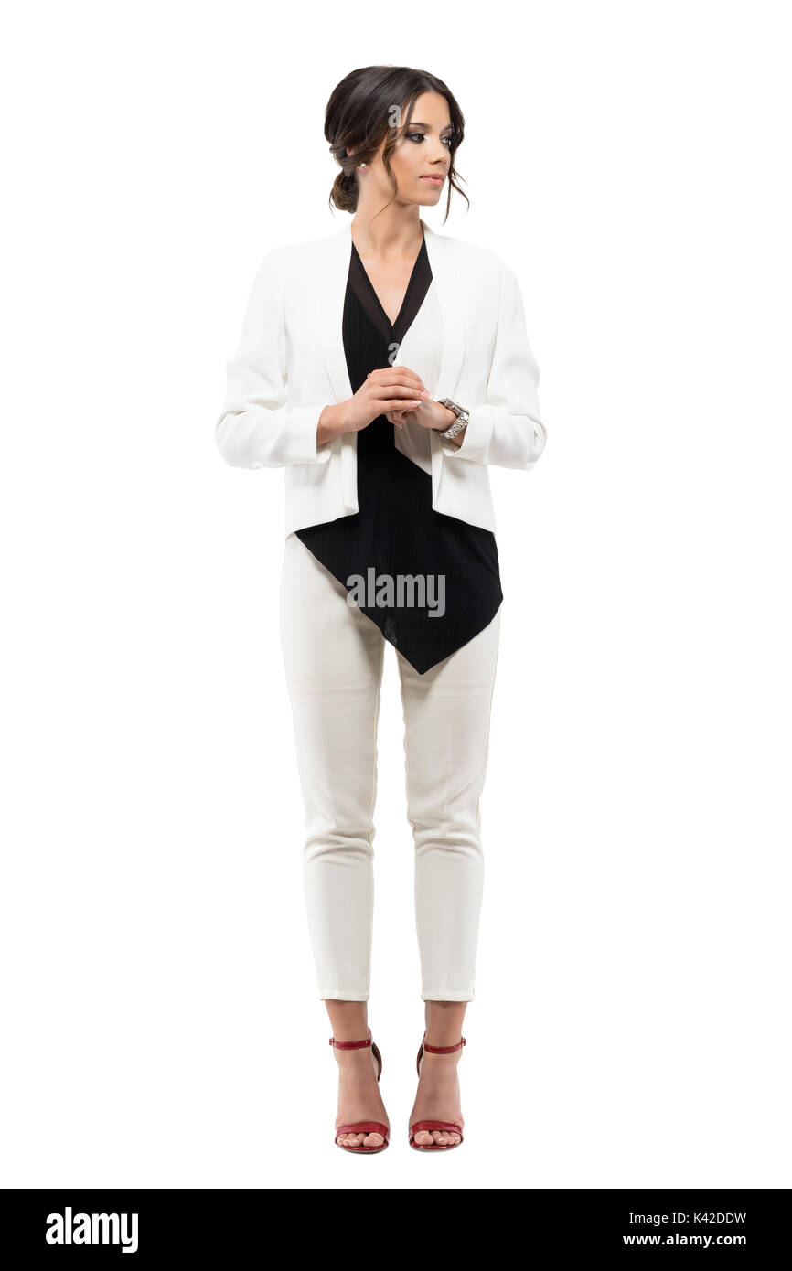 Elegante business Frau in Anzug in formale Haltung mit gefalteten Händen weg schauen. Voller Körper Länge Porträt auf weißem Hintergrund Stockfoto