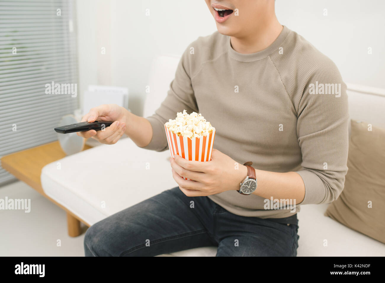 Junger Mann essen Popcorn und Filme entspannt auf der Couch zu Hause Stockfoto