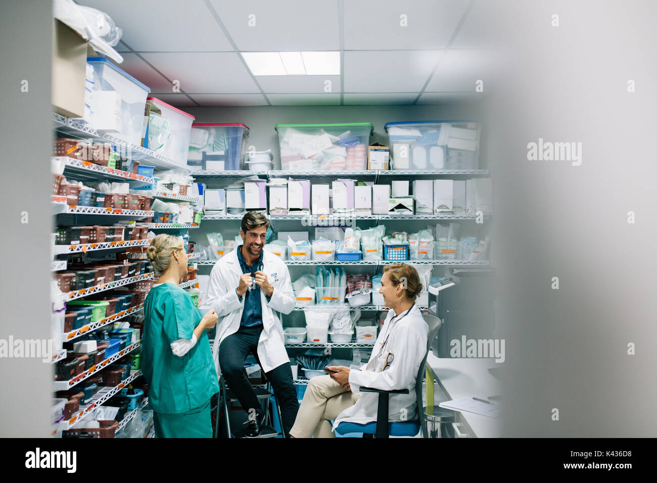 Glücklich das medizinische Personal in zwangloser Diskussion in der Apotheke. Drei Kollegen treffen in Apotheke und lächelnd. Stockfoto