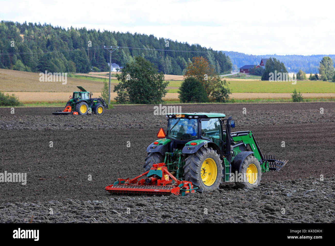 SALO, Finnland - 20. AUGUST 2017: Landwirte Feld kultivieren mit zwei John Deere Traktoren sowie Kverneland Eggen an einem schönen Tag der frühen Herbst. Stockfoto