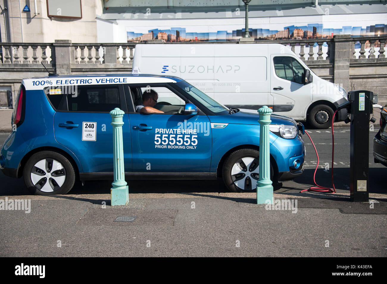 Ein elektrisches Auto zu einem aufladen Punkt in Brighton. Ein Taxi Fahrer wartet, als sein Fahrzeug aufgeladen wird. Credit: Terry Applin Stockfoto