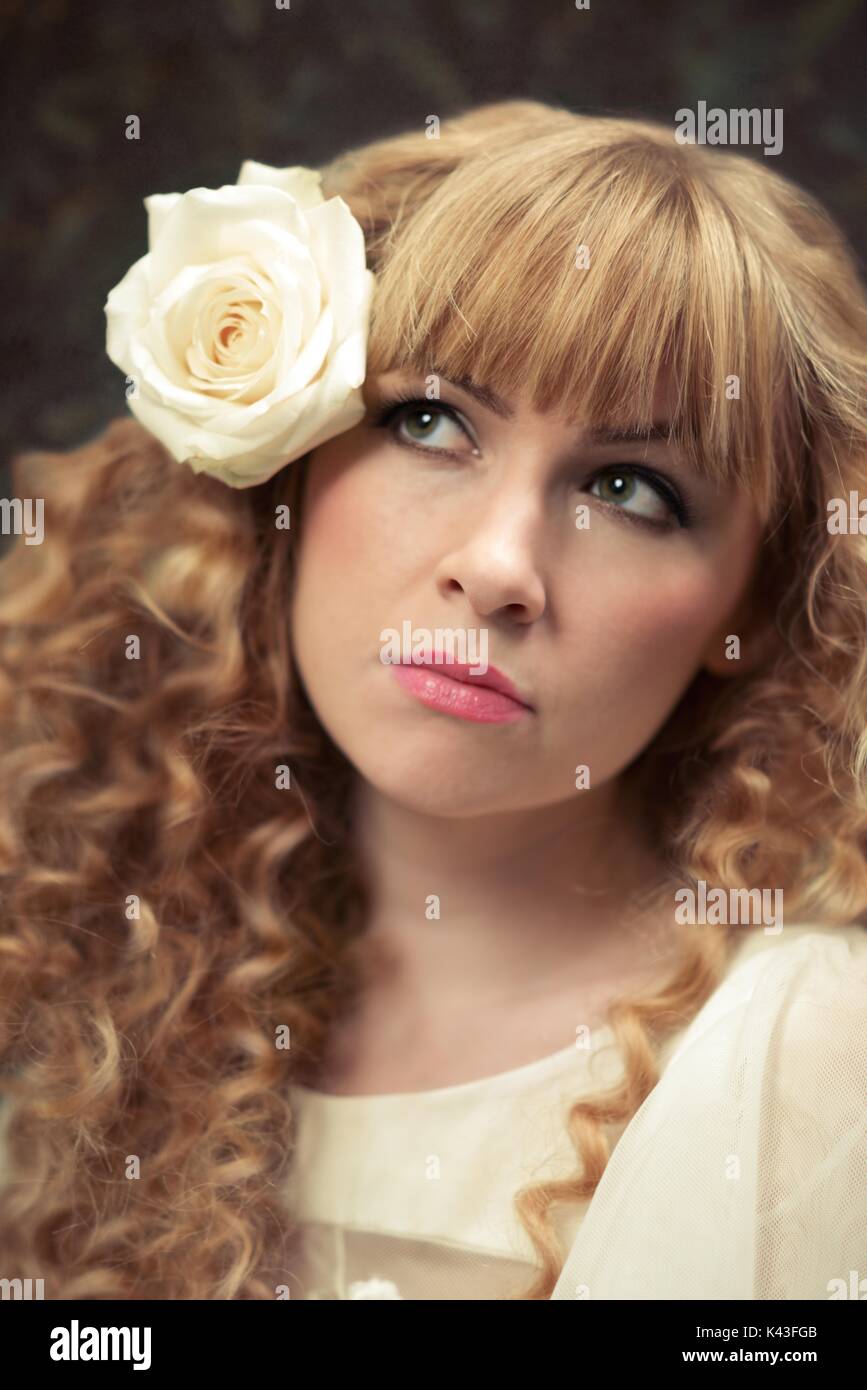 Nahaufnahme des Frauengesichts mit weißer Rose in ihrem langen blonden Haar Stockfoto